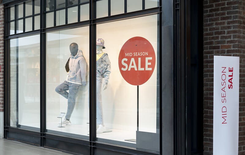 An image of sale signage next to a display window for a store.